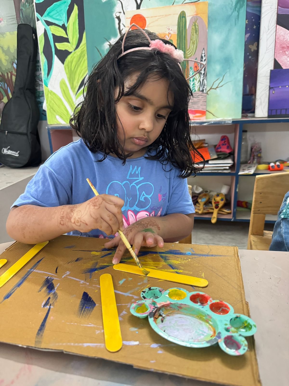 A girl carefully painting a wooden craft piece