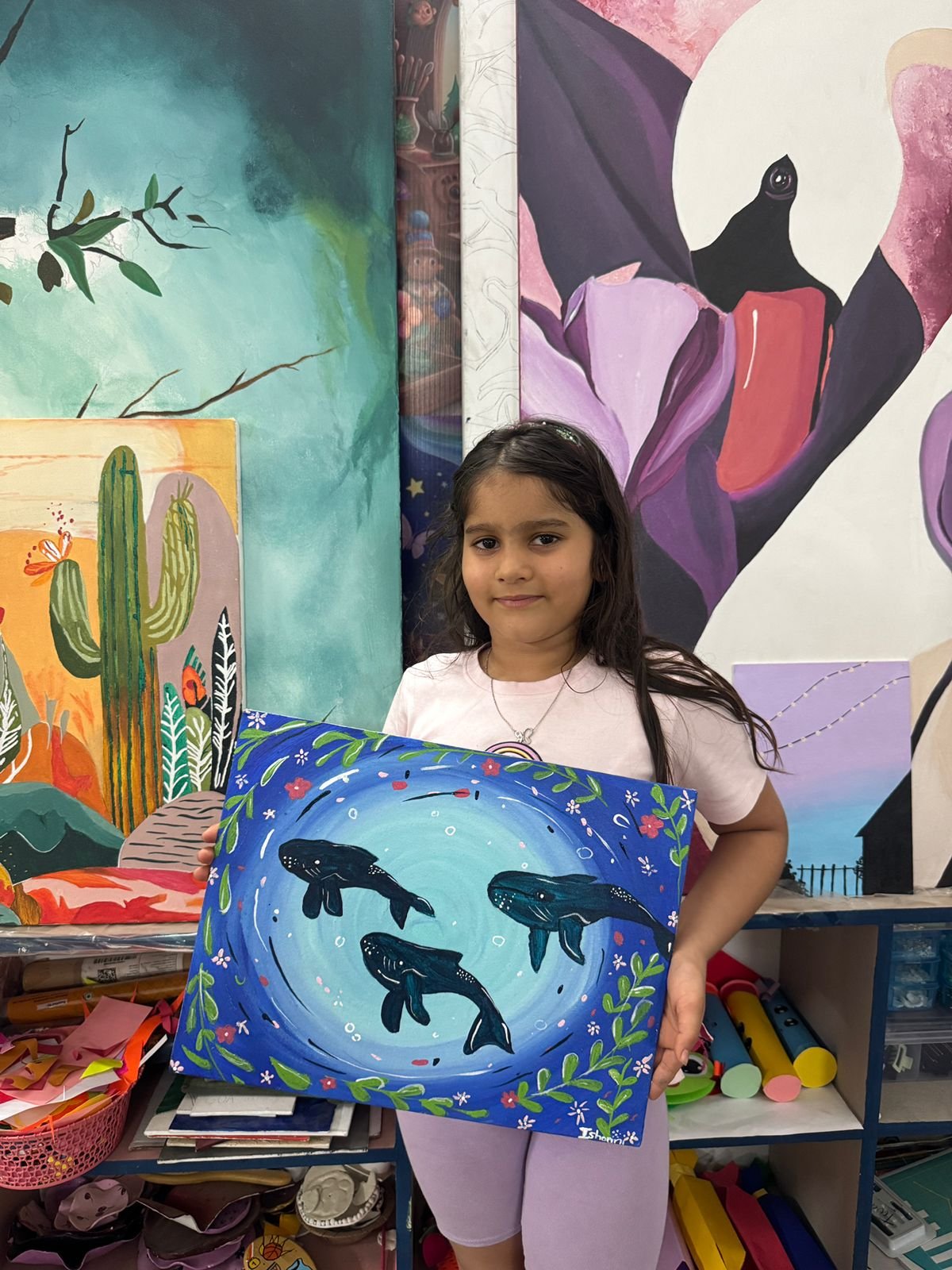A girl holding her detailed whale-themed painting