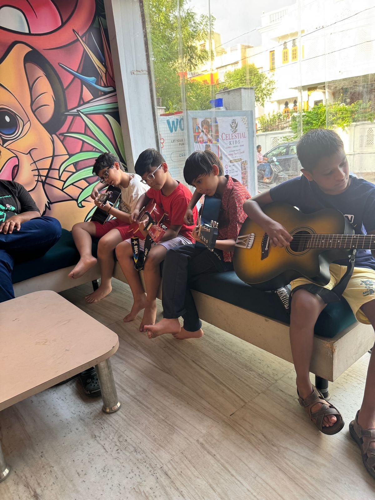 A group of children learning guitar together in a music class at Celestial Kids
