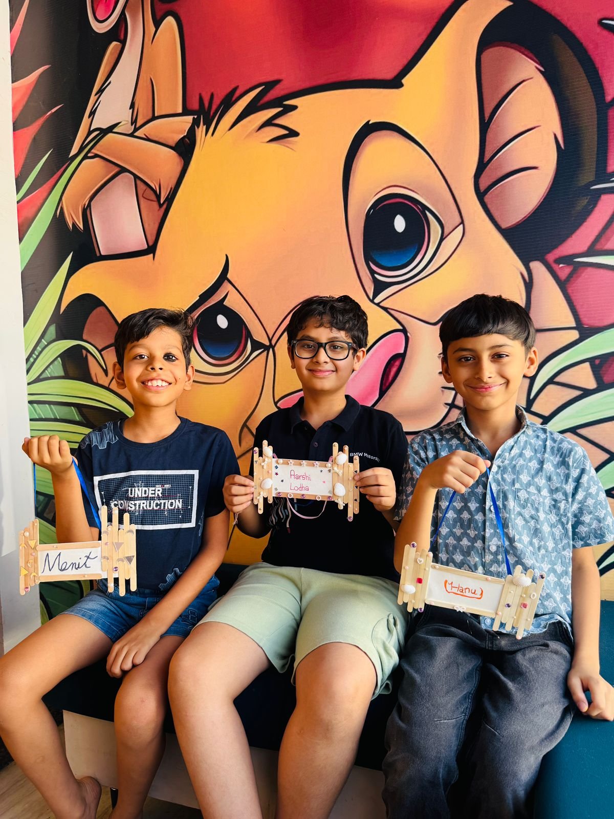 Three boys holding their handmade popsicle-stick name plaques
